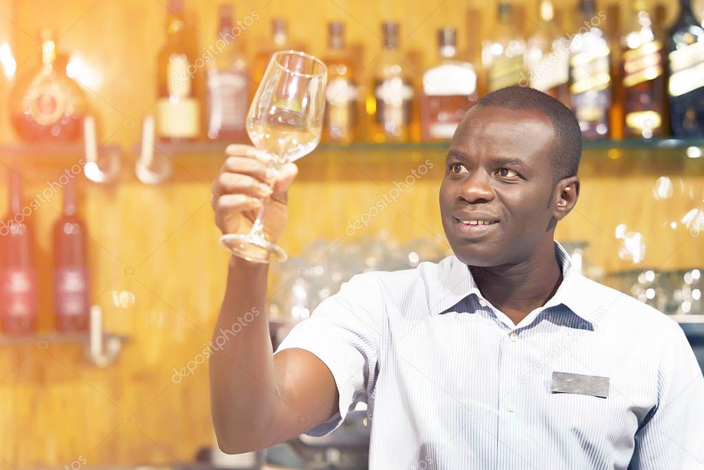 African bartender wipes out the wine glass at work.