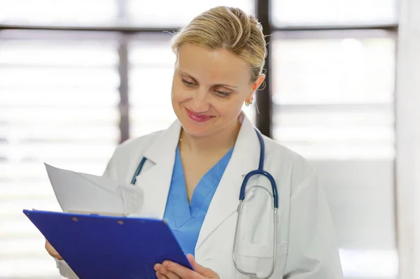 Cheerful female doctor is holding documents with patient informa