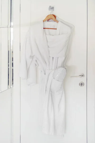 Peignoir blanc suspendu sur un étagère. Robes de chambre d'hôtel sur le cintre de porte . — Photo