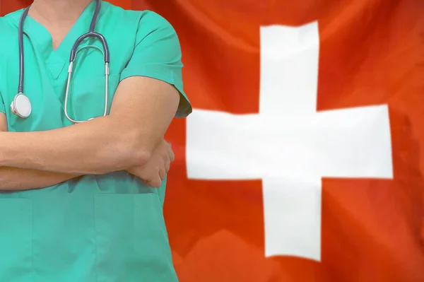 Male surgeon or doctor with stethoscope on the background of the Switzerland flag. Health care and medical concept. Surgery concept in Switzerland.