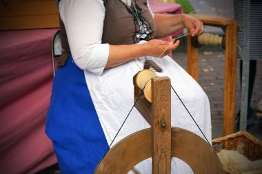 Eski bir çarkta dönen geleneksel yünleri gösteren bir kadının elleri. Dönen çarkın üzerinde dönüyor. Yünü ipliğe dönüştürmek için eski bir çark kullanan usta kadın. Dönen tekerlek.