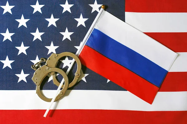 Russia flag in handcuffs on the background of the American flag. US sanctions against Russia.