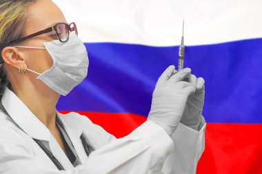 Kadın doktor ya da eldivenli hemşire Rusya bayrağının arka planına karşı aşı için şırınga taşıyor. Tıp konsepti ve virüsle savaş. Rusya 'da Coronavirüs.