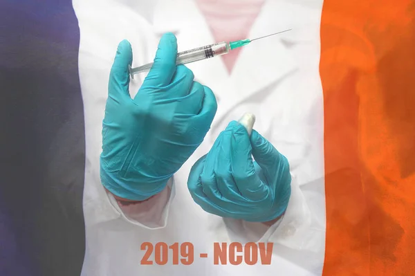 Hand of doctor or nurse in blue gloves holding syringe for vaccination against the background of the France flag. Medicine concept and fight the virus. China coronavirus in France.