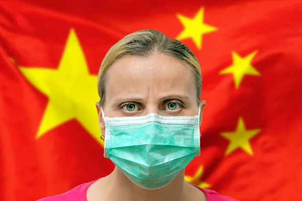 Masked woman face looking at the camera on flag China background. The concept of attention to the worldwide spread of the coronavirus worldwide. Coronavirus, virus in China.