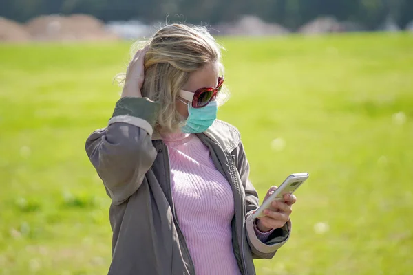 Woman wearing medical mask in street in city and speaks on the phone. Woman walking on the street wearing protective mask as protection against infectious diseases.