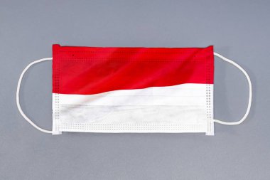 Gri arka planda Monako bayrağı olan izole tıbbi maske. Yakından koruyucu maskeler tekstil filtresi. Sağlık ve tıbbi konsept. Coronavirus, Monako 'daki virüs..