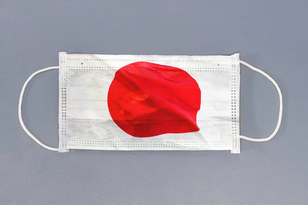 灰色の背景に日本の旗を持つ隔離された医療用マスク 保護マスク繊維フィルターを閉じます 医療と医療の概念 日本のウイルス コロナウイルス — ストック写真