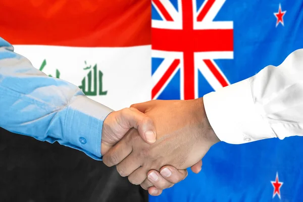 在两面旗帜的背景下进行商业握手 男子在伊拉克和新西兰国旗的背景下握手 支助概念 — 图库照片