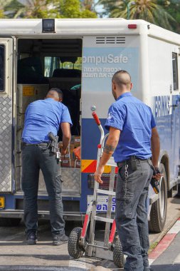 Silahlı korumalar para taşıyor. Brink 's Company' nin kamyonetindeki iki muhafız para çantalarını arabaya koydu. Zırhlı araçlar. 11 Kasım Tel Aviv, İsrail.