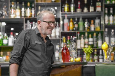 Barmen masaya servis yapıyor. Barmen, bardaki bir otel restoranında şarap kadehi ve şarap şişesi taşıyor. Hizmet kavramı.