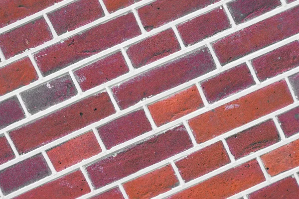 Photo of a sloping dark red brick wall. Dark red Brick wall for background or texture. Old red brick wall texture background.