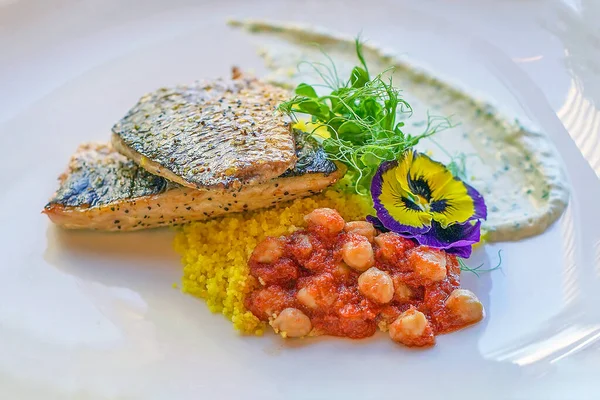 Restorandaki masada, balık derisi çıtır kraker, kuskus ve nohut ile mükemmel hazırlanmış kefal bifteği. Kefal balıklı tabak. Bir tabak Yeni Zelanda kefal balığı..