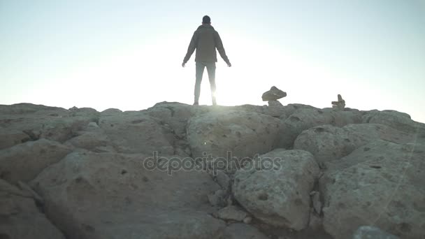 Hombre de pie al borde de una montaña desierta con los brazos abiertos — Vídeo de stock