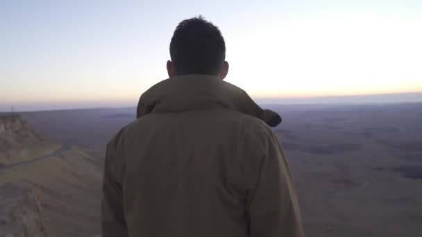 Homem olhando para a vista do deserto a partir da borda de um penhasco — Vídeo de Stock