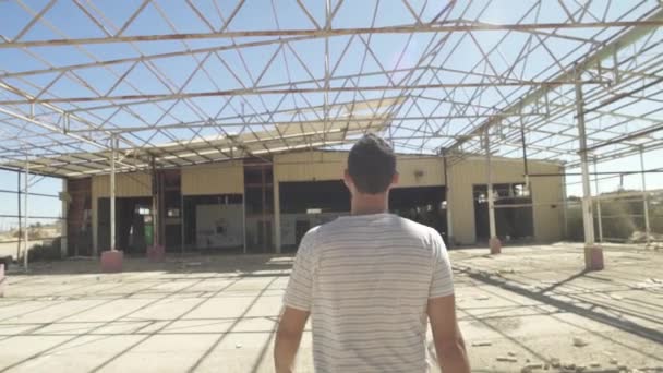 Tracking shot di un uomo che cammina in una fabbrica abbandonata — Video Stock