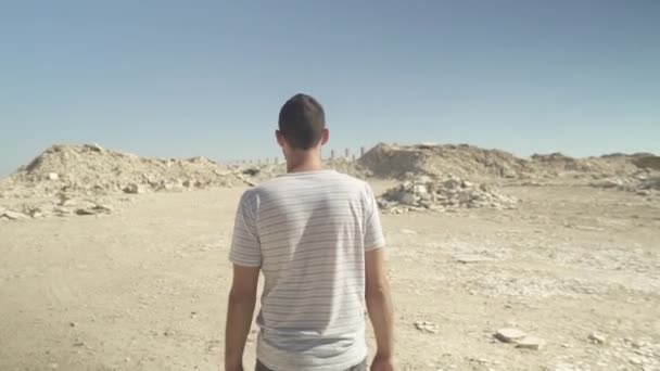 Молодой человек идет рядом с разрушенными обломками — стоковое видео