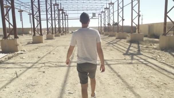 Fiatal férfi sétál egy elhagyott hangár — Stock videók