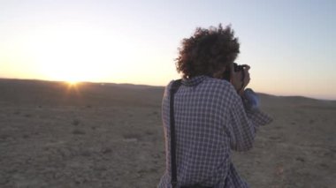 Çöl güneşi altında bir fotoğrafçı bir fotoğraf çeker.