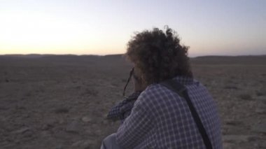 Genç fotoğrafçı bir fotoğraf çekerken diz çöker