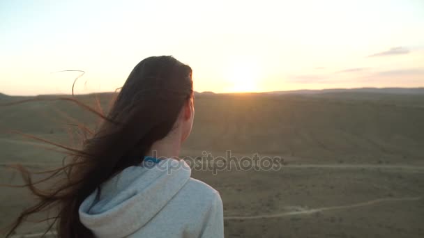 Mujer joven mirando la puesta de sol en el desierto — Vídeo de stock