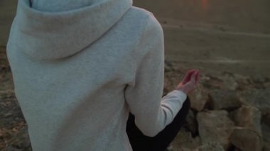 Genç kadın meditasyon bir çöl tepe üzerinde günbatımında yapıyor.