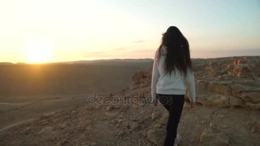 Güzel bir gün batımı sırasında bir çöl tepe tırmanma kız