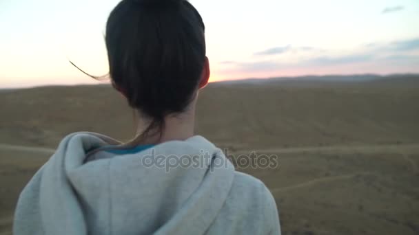 Joven hembra de pie en la cima de una montaña mirando al sol — Vídeo de stock