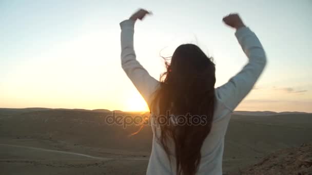 Mladá žena Zvedněte ruce ve vzduchu během pouštní západ slunce — Stock video