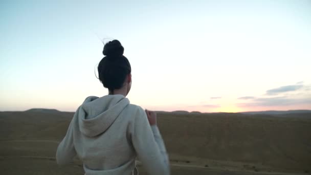 Joven mujer pone sus manos en alto en un hermoso atardecer desierto — Vídeo de stock