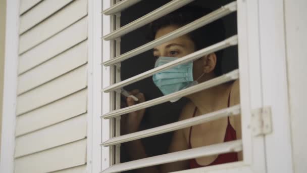 Neugierige Oder Besorgte Junge Frau Mit Mundschutz Guckt Aus Fenster — Stockvideo