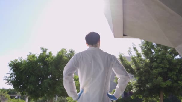 医療や研究室のコートの若い男はしっかりと研究室や建物の隣に立つ — ストック動画