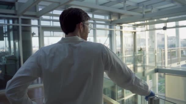在实验室或医院里 穿着实验室外套的年轻人骄傲地凝视着地平线 — 图库视频影像