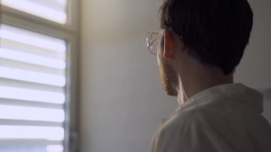 Bilim adamı ya da doktor laboratuvar penceresinden güneşin doğuşuna gururla bakıyor.