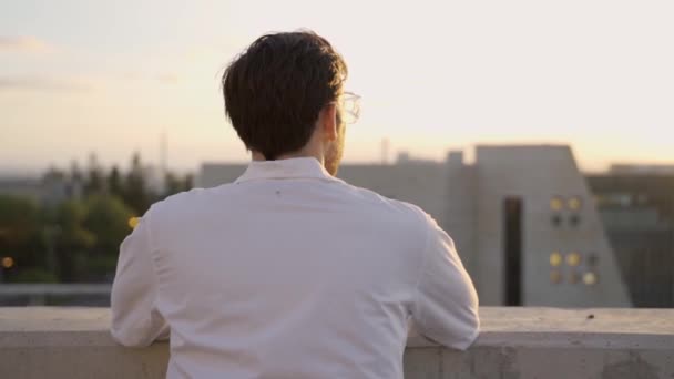 一个穿着实验室外套的男人站在一座大楼外面看着太阳 — 图库视频影像