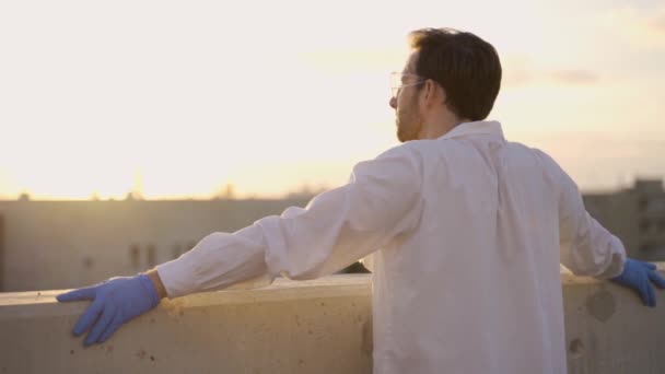 地平線を見る研究室のコートと手袋を持つ若い医師または研究者 — ストック動画