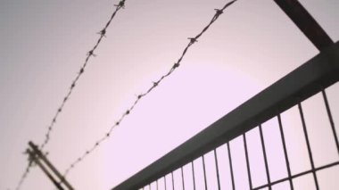 Şehrin güneşli bir gününde metal bir çitin üzerindeki dikenli tel.