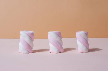 Three cute bright marshmallows sweet candy on minimalistic pink 