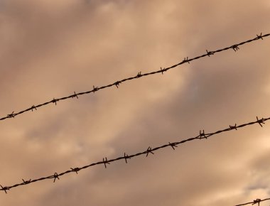 karanlık bir tehditkar gökyüzü önünde dikenli tel