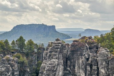 Sakson İsviçre 'nin Elbe Kum Taşı Dağları' nda yürüyüş ve tırmanma manzarası dramatik bulutlu bir gökyüzü ve Ferdinandstein denilen kaya oluşumları, arka planda Lilienstein ve Kingstone yükseklikleri. Manzaradan bak