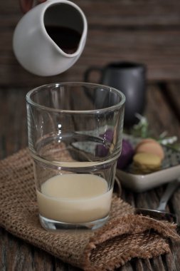 Klasik natürmort el ile sıcak kahve bir bardak süt, dikey vintage resim için yağıyor.