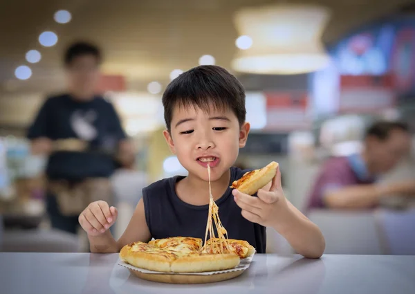 Asian boy is happy to eat pizza with a hot cheese melt stretched — Stock Photo, Image