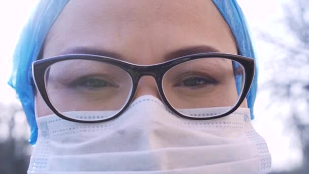 Salud en la pandemia del Coronavirus Covid19. Persona que usa máscara protectora y gafas al aire libre mirando a la cámara y luego hacia adelante. Detener la infección por COVID-19. Clip ProRes 422, grabado en 4K UHD . — Vídeos de Stock