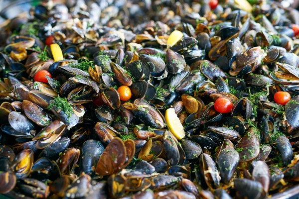 Zubereitete Miesmuscheln in Weinrebe und cremiger Sauce mit Knoblauch, Gemüse und kleinen Tomaten. Ursprüngliche mediterrane Küche. Nahaufnahme von frischen Meeresfrüchten. Ansicht von oben. — Stockfoto