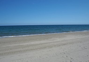 mavi gökyüzü ve sakin deniz ile temiz boş kum plaj