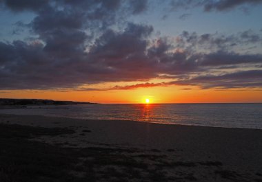 kumüzerinde denize inen kırmızı turuncu güneş ile gün batımı