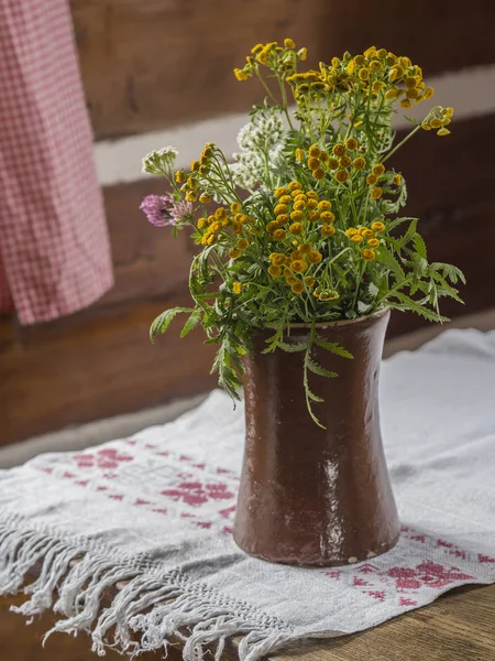 Florero de cerámica marrón con flores de campo amarillas blancas y rosadas en —  Fotos de Stock