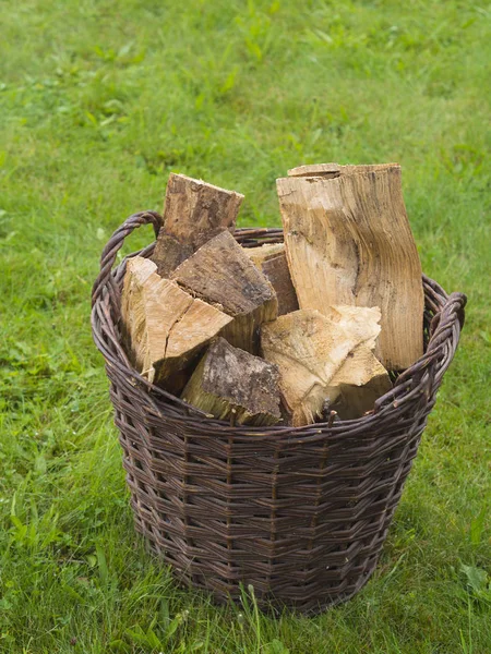 Cesta de mimbre llena de madera picada sobre fondo de hierba verde — Foto de Stock