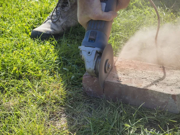 hands of man cutting brick working with portable circular saw on