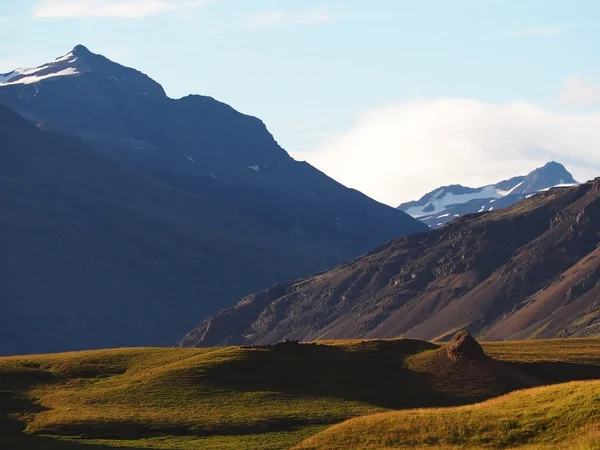 Vista de las montañas cubiertas de nieve y verdes colinas de hierba por la noche — Foto de Stock